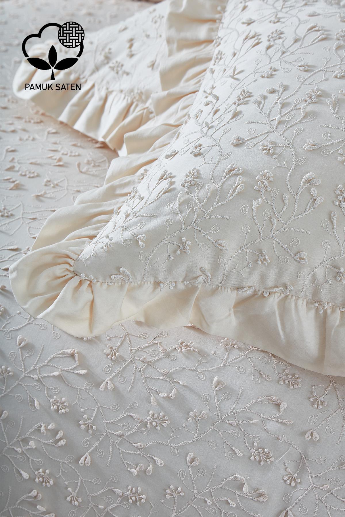 Parure de lit double en satin de coton crème brodé, avec motif floral et taies à volants.