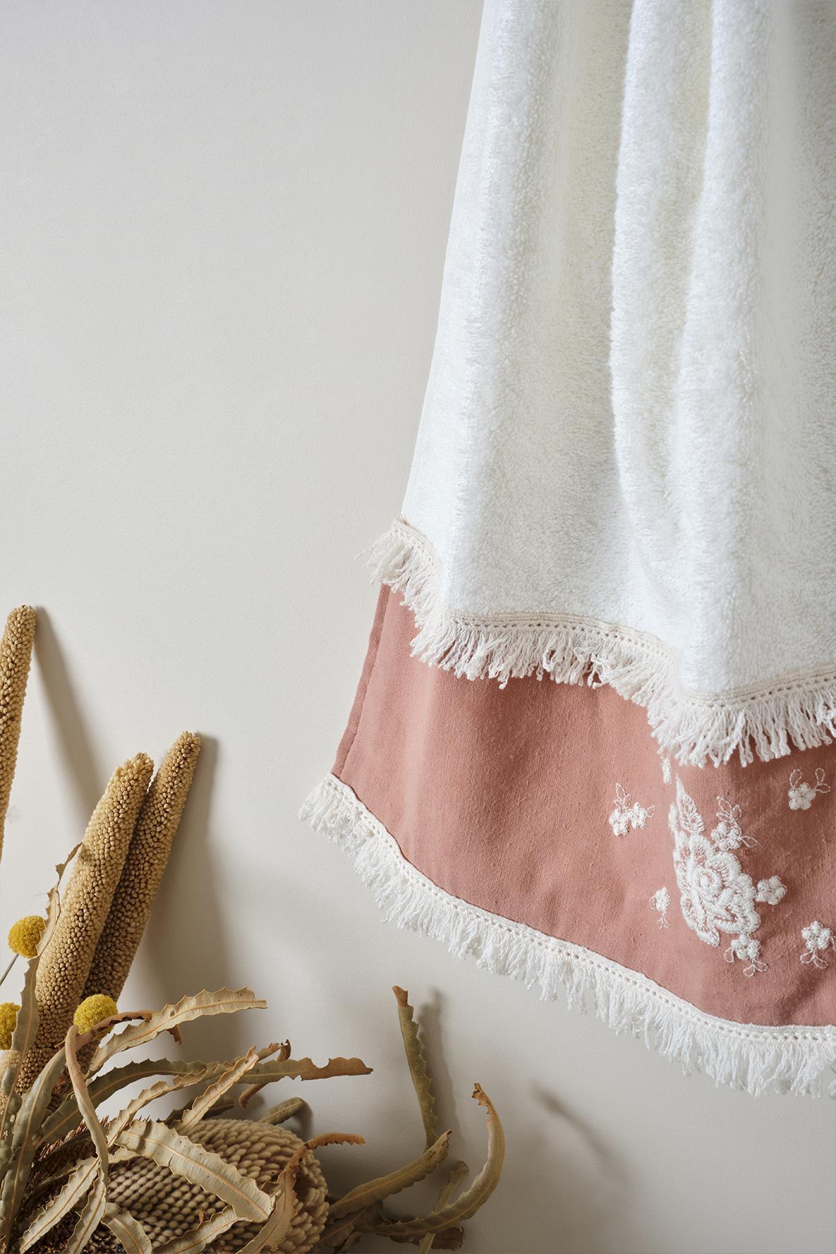 Serviette décorative 50x90 cm, brodée bordeaux avec bords à pompons, suspendue dans un environnement naturel