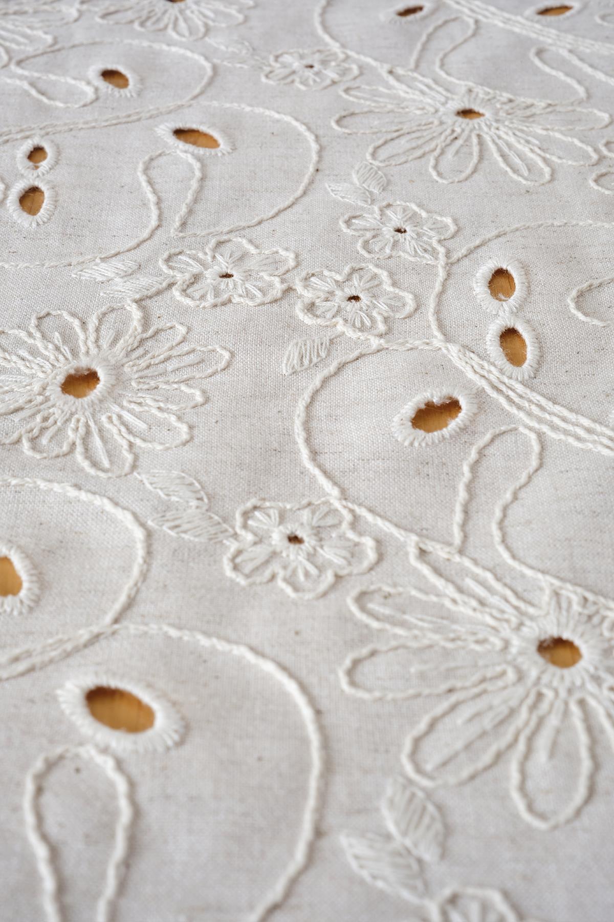 Vue détaillée d'un chemin de table en coton tissé couleur crème à motif floral