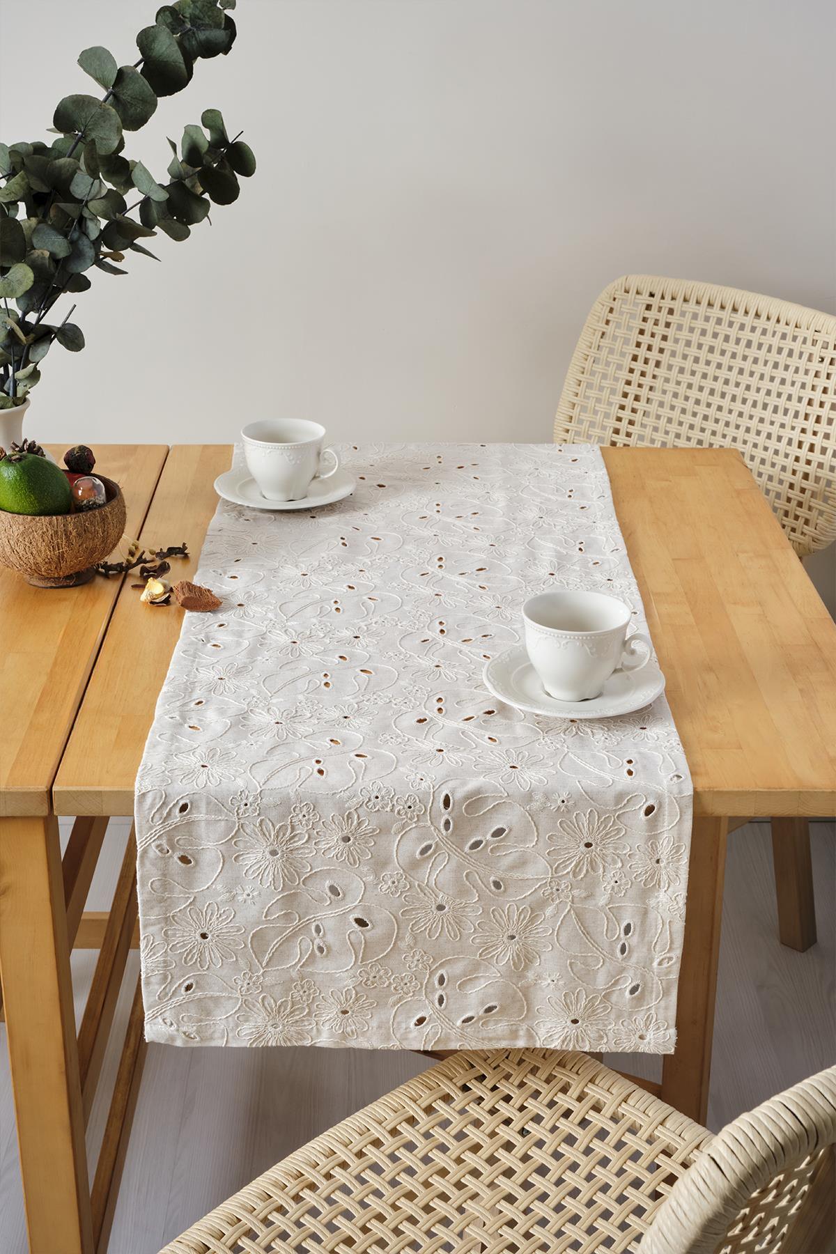 Chemin de table crème à broderies en dentelle, présentation décorative avec deux tasses sur une table en bois