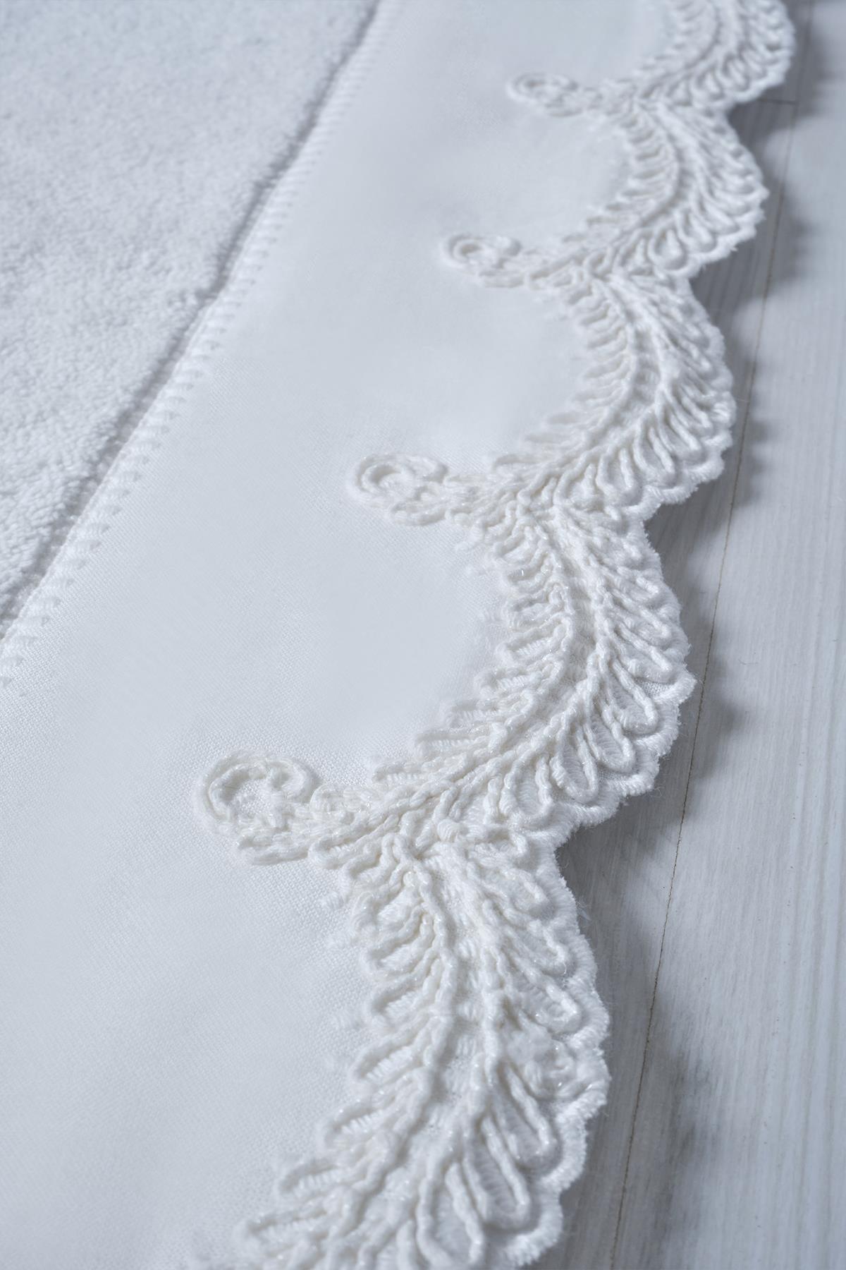 Gros plan sur un tapis en coton blanc avec des détails en dentelle