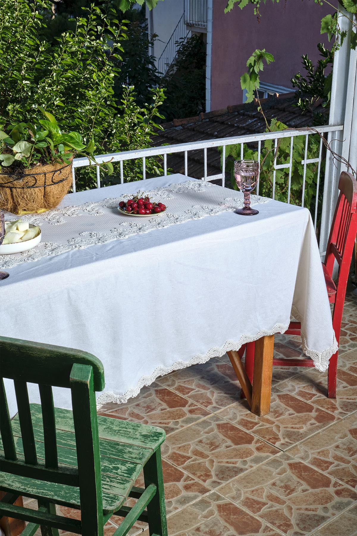 Table de balcon recouverte d'une nappe blanche avec détails en dentelle, accompagnée d'une chaise rouge et d'une chaise verte