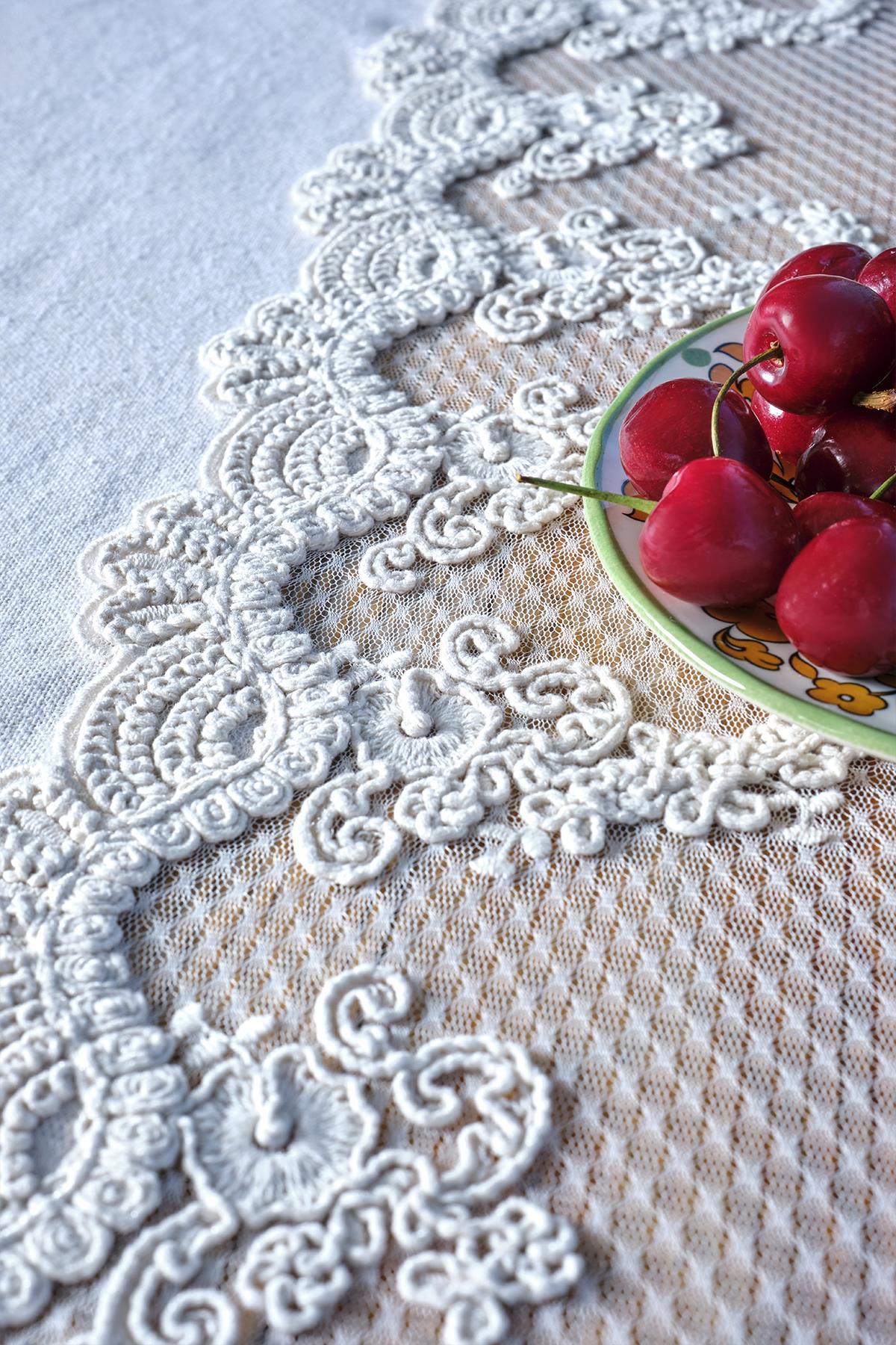 Nappe blanche en dentelle avec un gros plan de cerises dans une assiette posée dessus