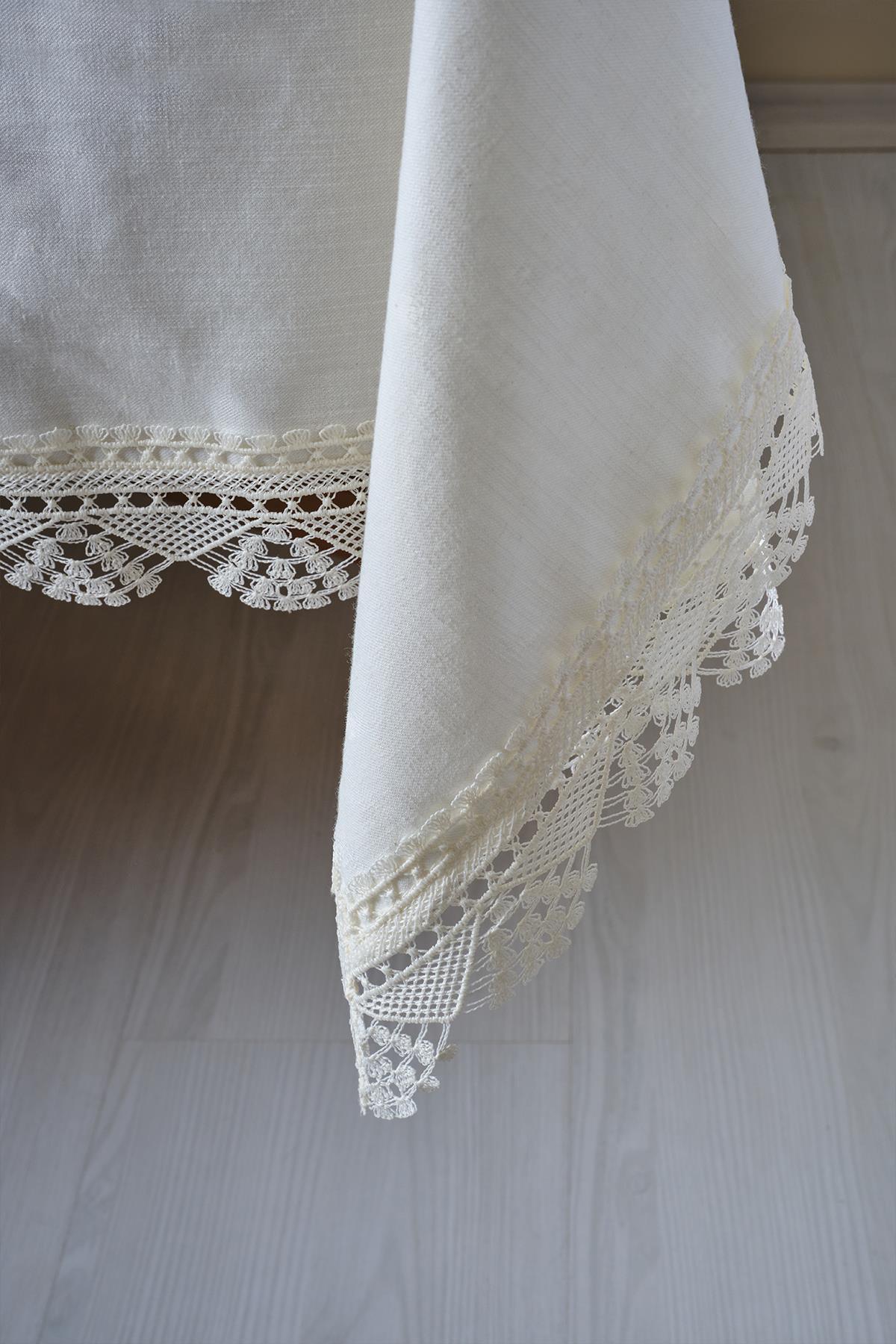 Vue d'angle d'une nappe crème antitache avec détails en dentelle