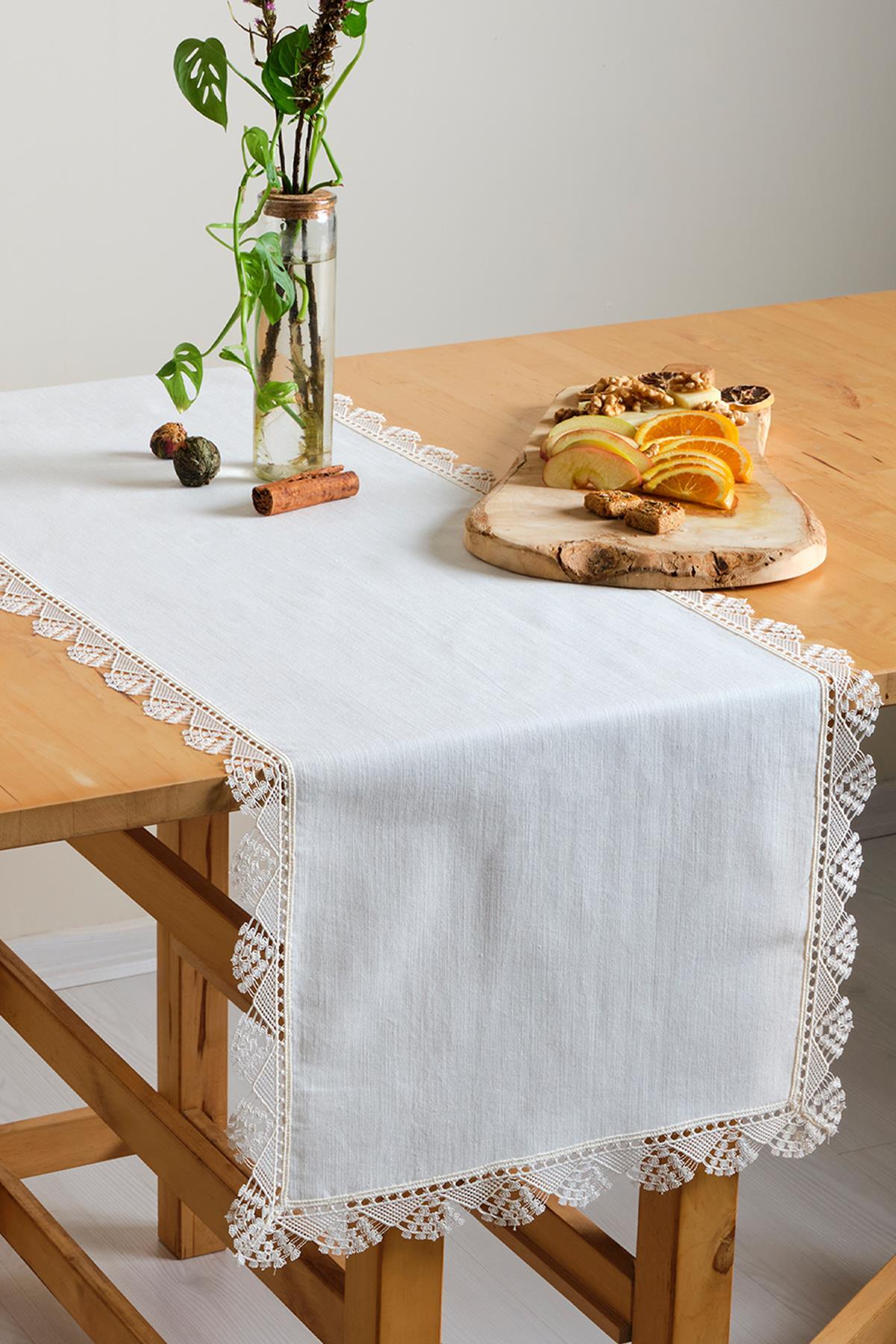 Chemin de table blanc en dentelle, nappe décorée de fruits et d'une plante ornementale sur une table en bois