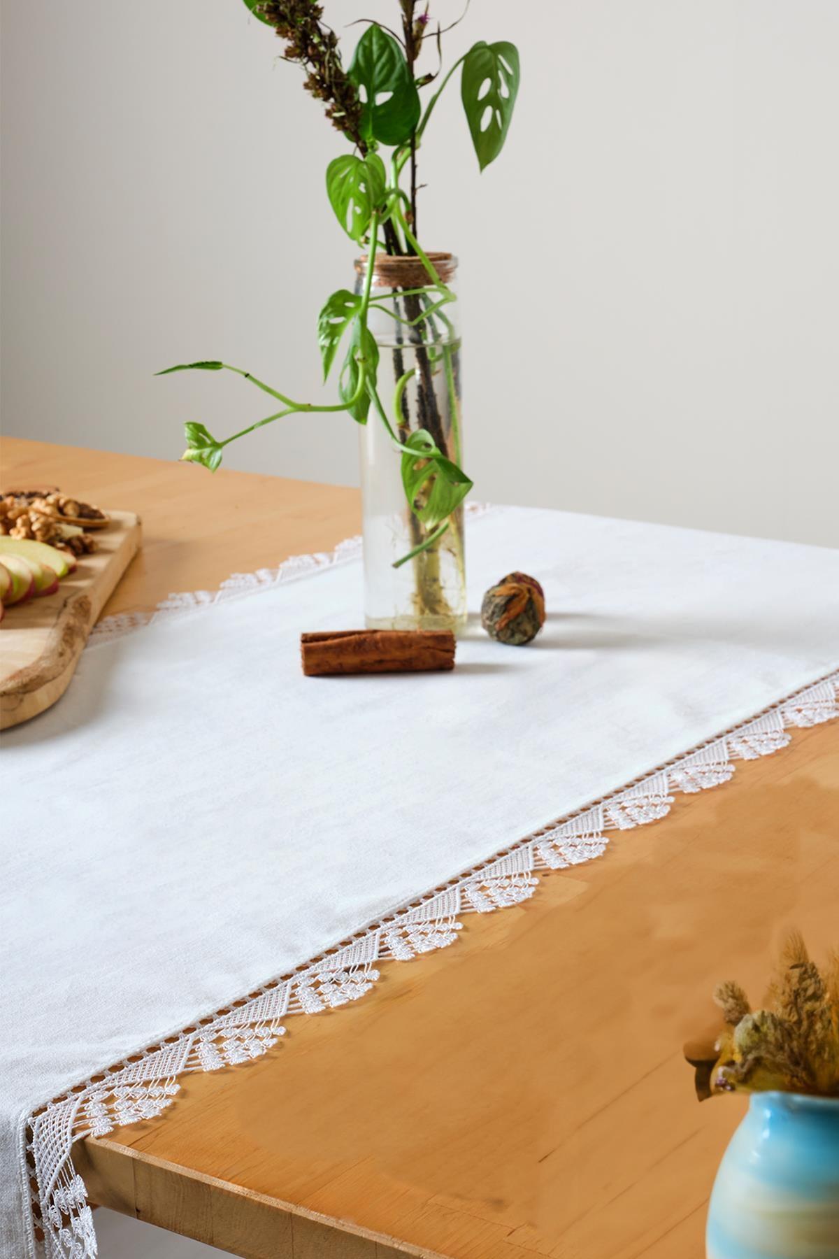 Chemin de table blanc en dentelle, offrant une décoration élégante et raffinée sur une table en bois.