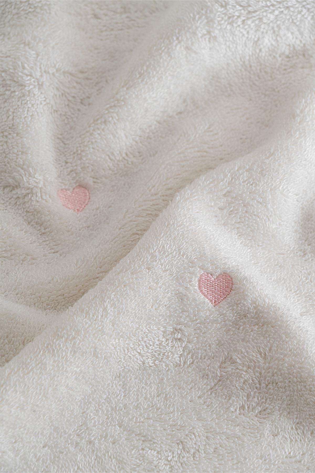 Serviette douce blanche avec détail cœur rose, pour un intérieur confortable et élégant
