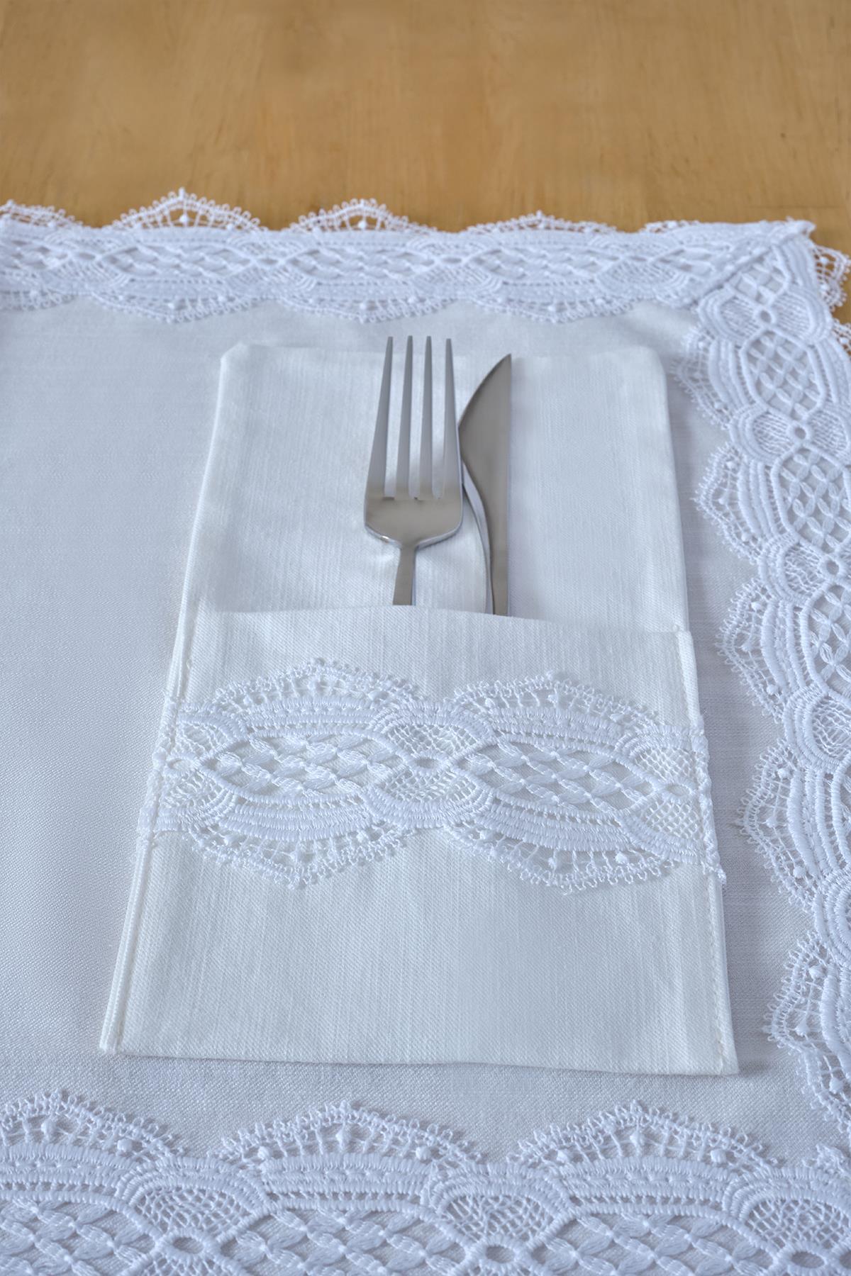 Porte-serviettes en tissu blanc avec broderies en dentelle, accompagné de couverts sur une table
