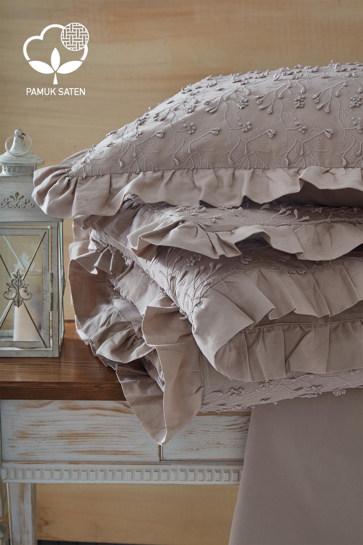 Parure de lit double en satin de coton brodé, avec détails en dentelle, présentée sur une table dans un coloris crème.