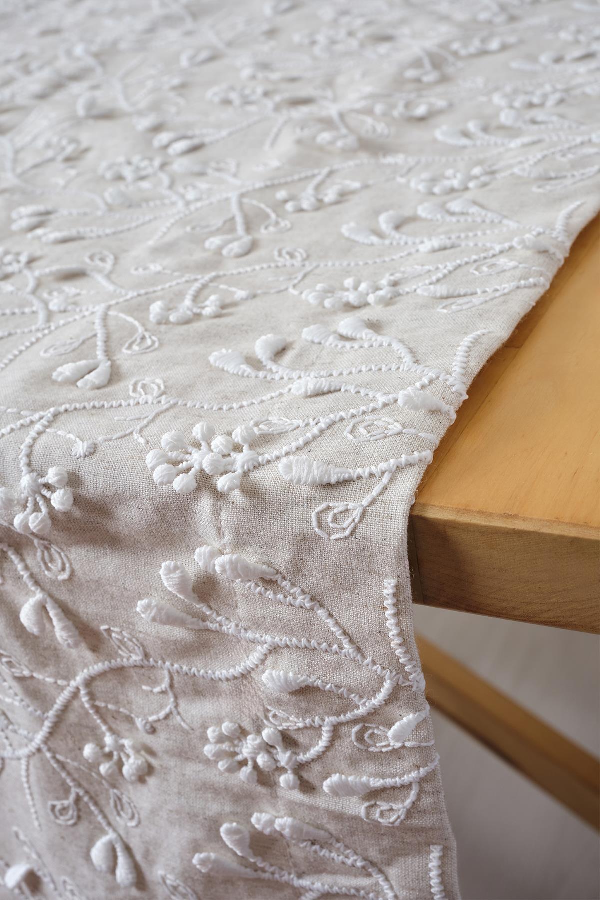 Chemin de table élégant sur fond beige avec broderies blanches, décoration moderne à motif floral