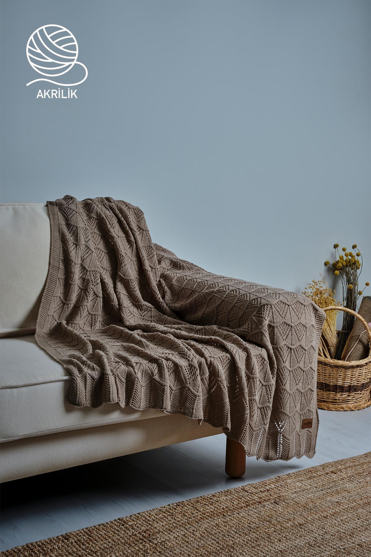 Couverture TV en tricot épais marron étalée sur un fauteuil crème, décor intérieur