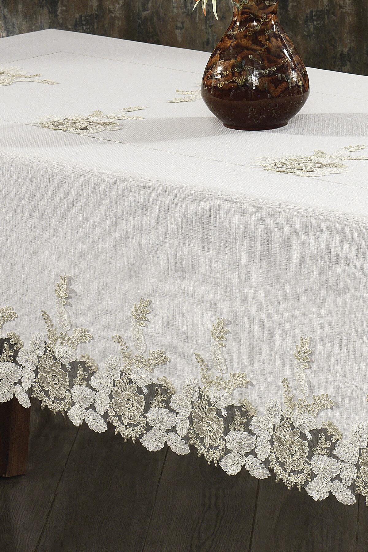 Nappe en dentelle couleur crème, antitache, présentée à côté d'une table élégante et d'un vase en céramique.
