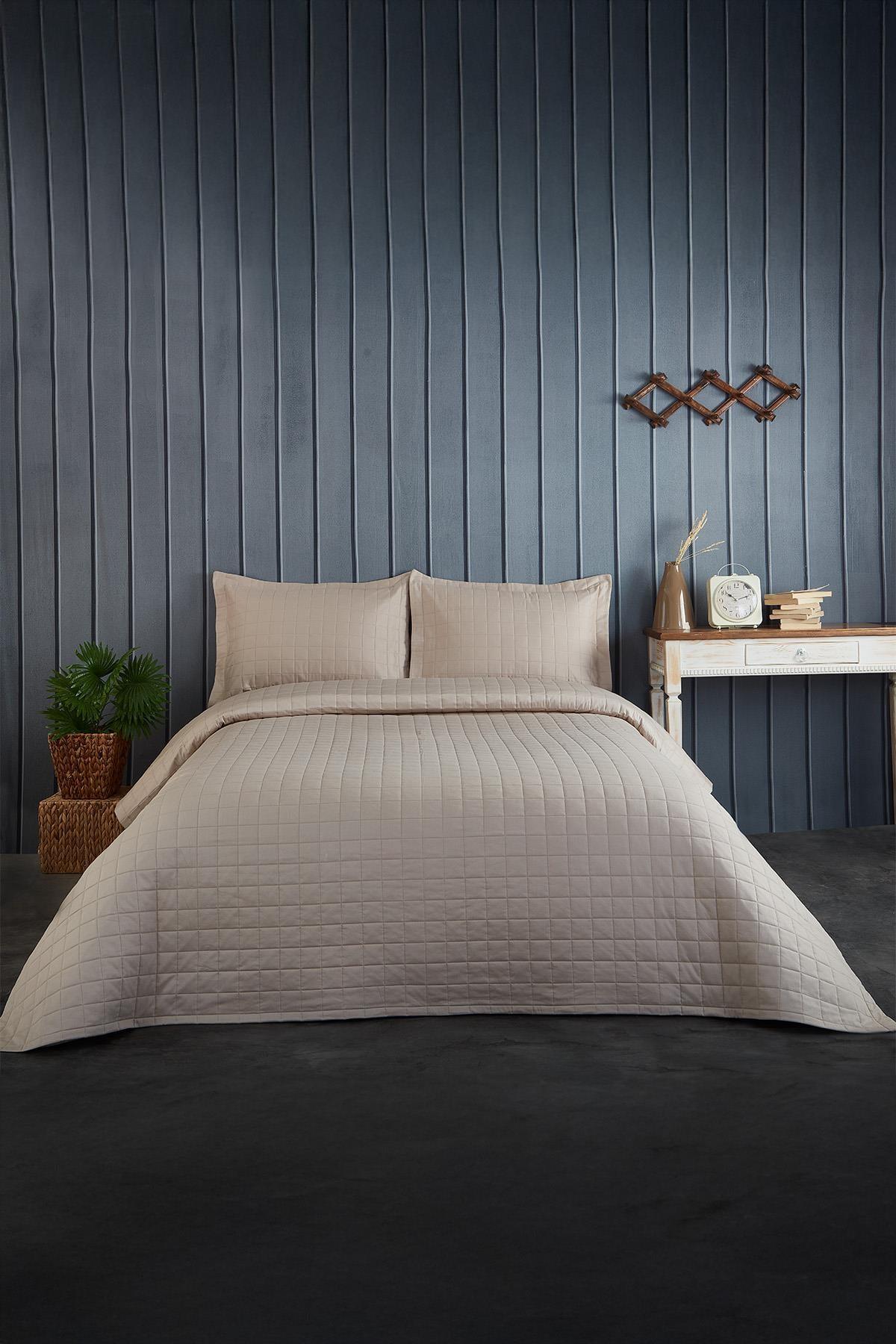 Couvre-lit double matelassé beige avec oreillers dans une chambre moderne