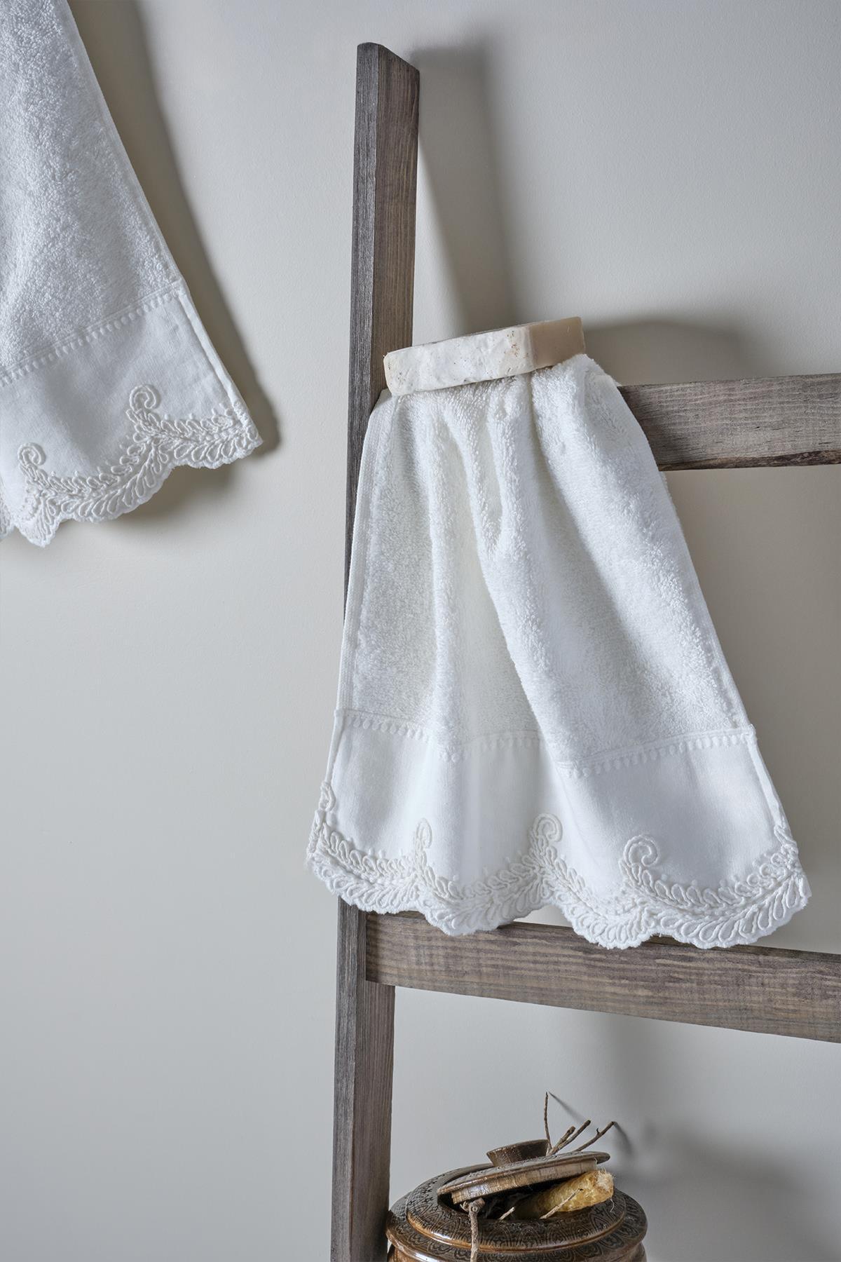 Serviette de corps blanche avec broderies en dentelle, sur une échelle en bois, avec des détails de bordure aux motifs élégants