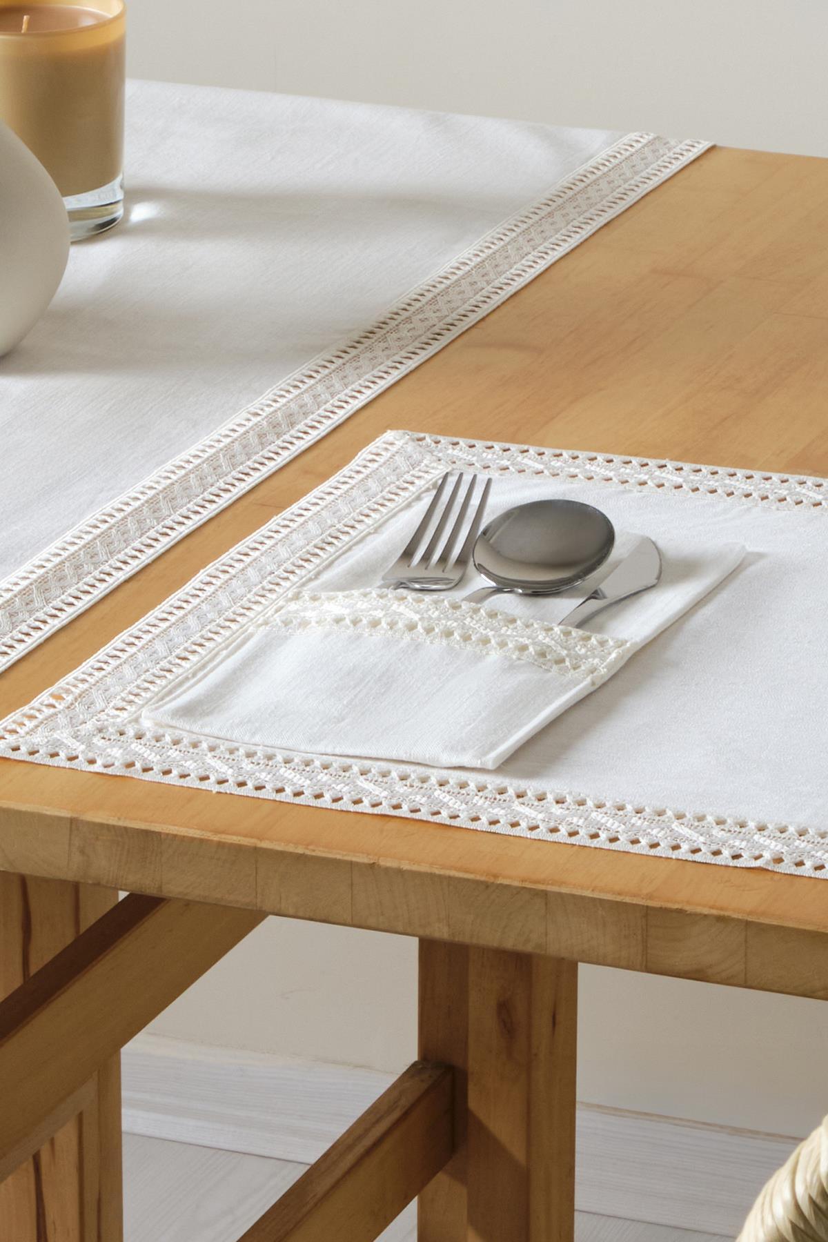 Nappe blanche en dentelle avec couverts (fourchette, cuillère, couteau) dans un porte-serviettes sur une table en bois