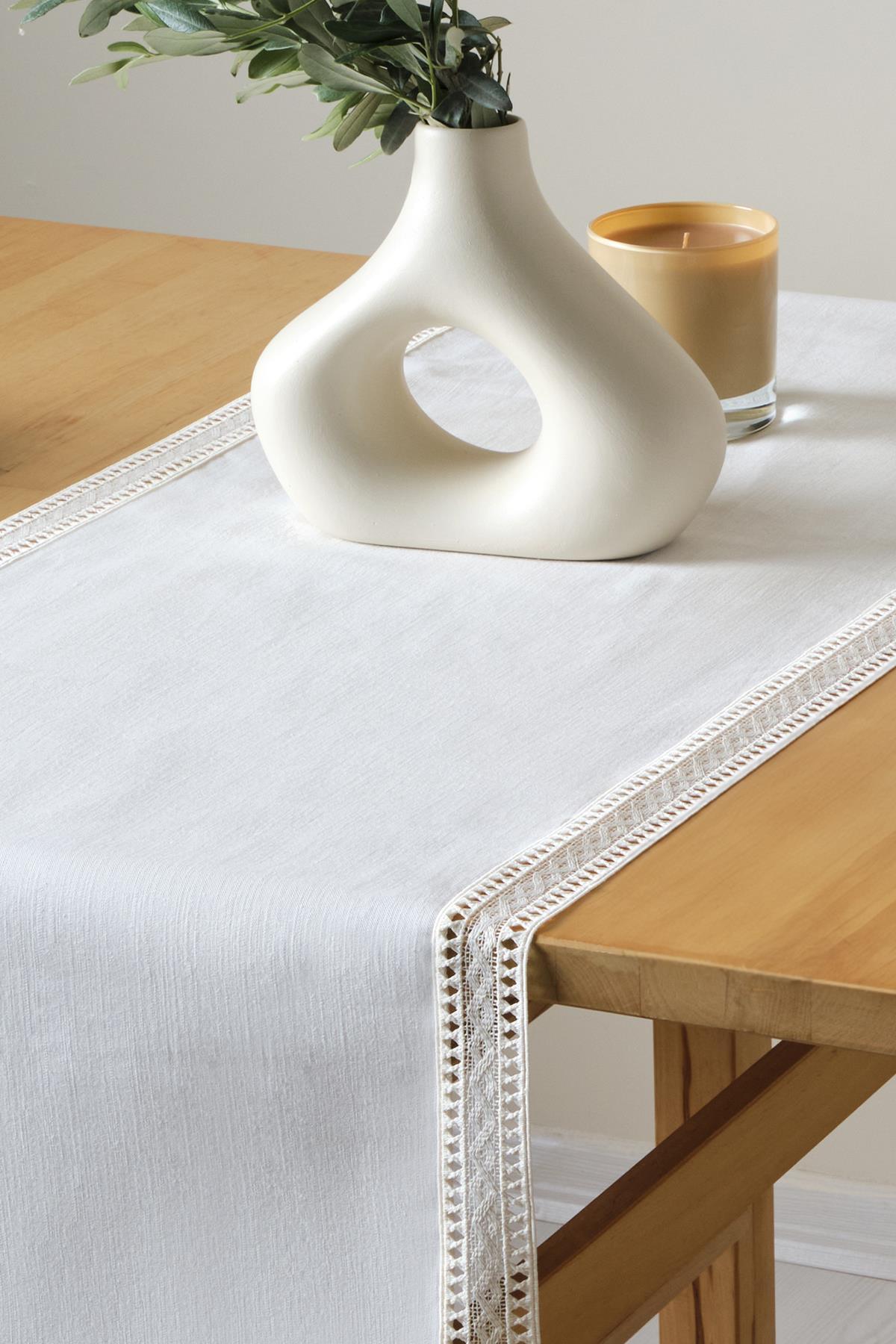 Chemin de table blanc en dentelle, présentation décorative avec vase moderne et bougie sur une table en bois