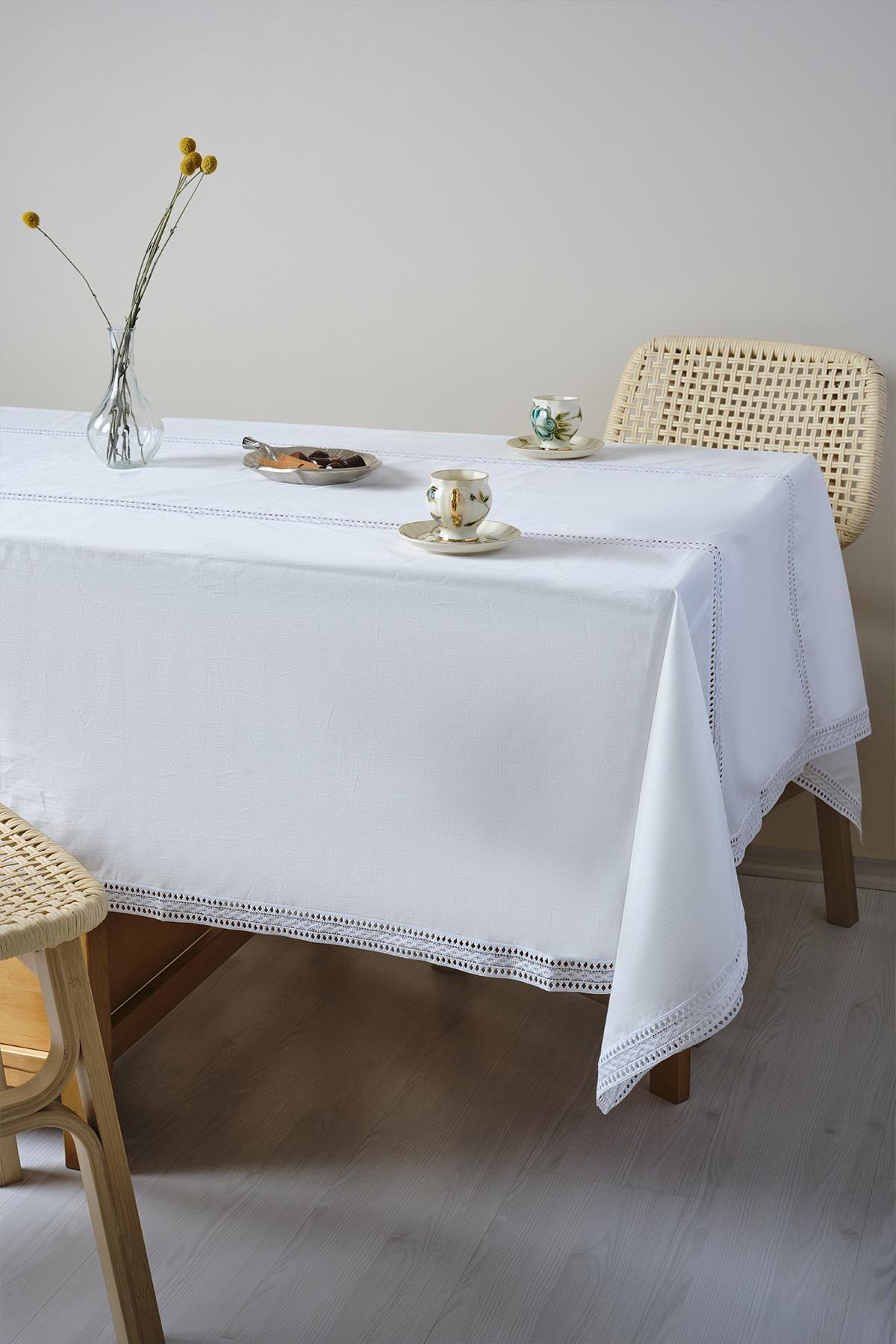 Table recouverte d'une nappe blanche, avec des tasses en porcelaine et un vase fleuri posés dessus