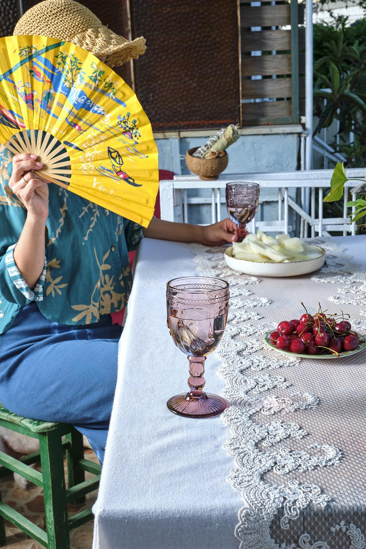 Nappe en dentelle sur une table en plein air, agrémentée de cerises et de verres élégants