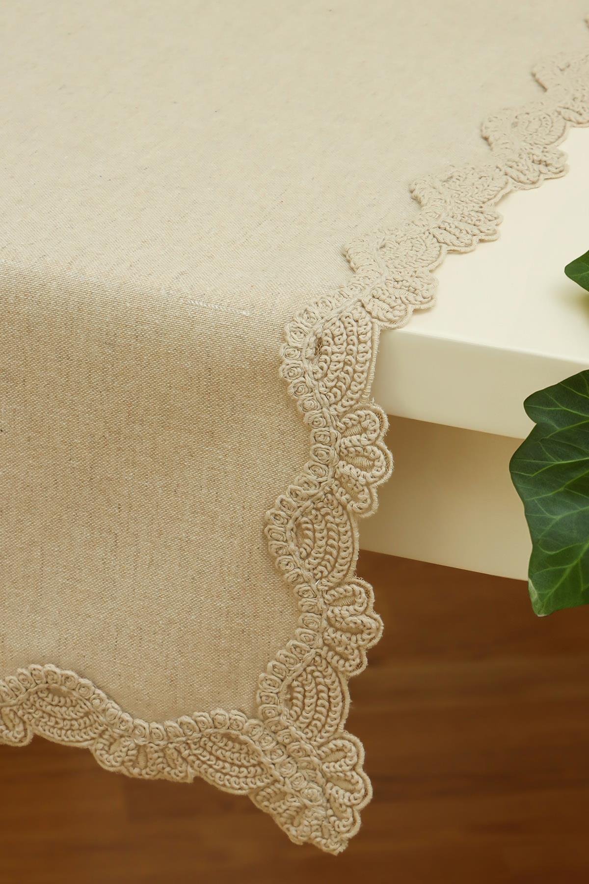 Nappe de table couleur crème avec bordure en dentelle, sur une table rectangulaire