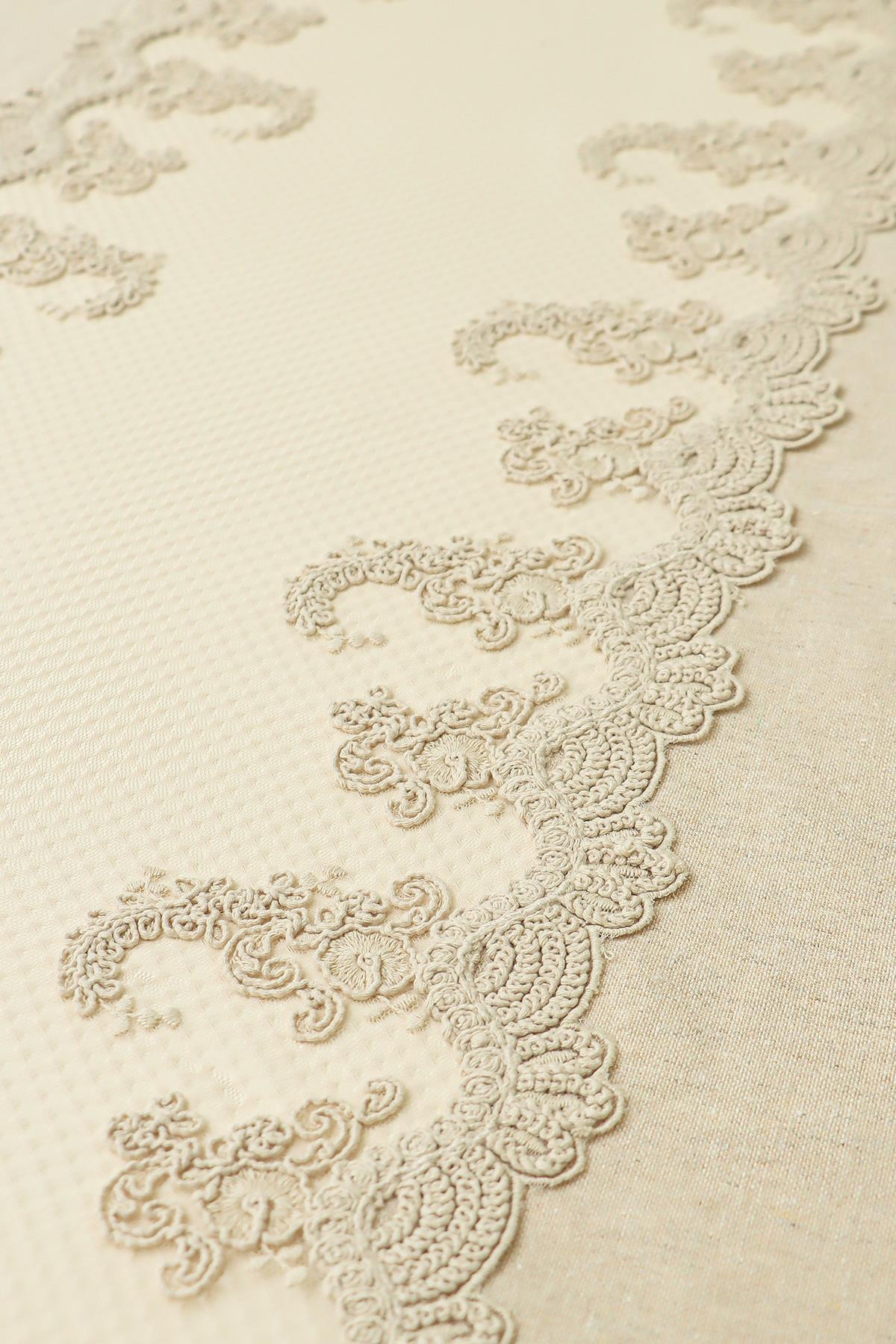Nappe couleur crème avec détails en dentelle, motif élégant et tissu texturé.