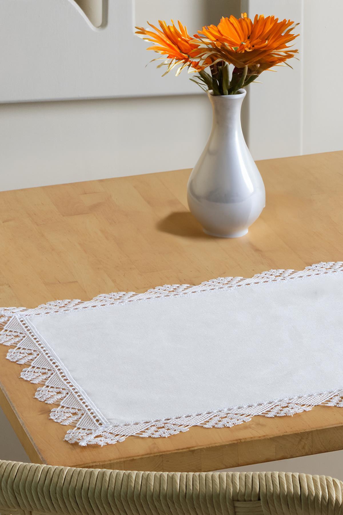 Chemin de table blanc à bordure en dentelle avec un vase décoratif sur une table en bois