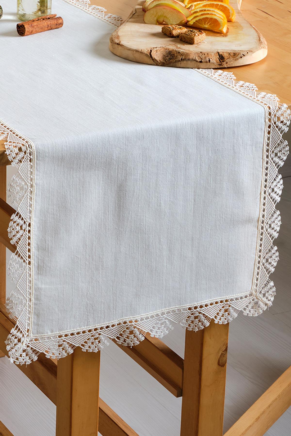 Chemin de table blanc en dentelle sur une table en bois, décoré de fruits et de biscuits.
